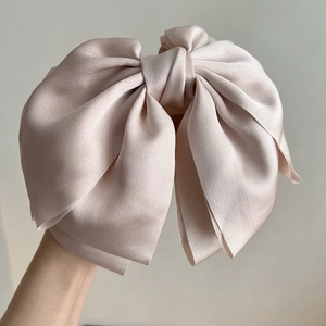 Dettaglio di un grande fiocco per capelli in raso rosa con trama di seta lucida ed elegante