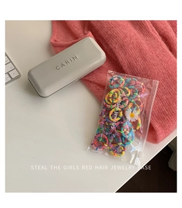 Detailed view of colorful elastic hair bands in a daisy zipper pouch on a desktop