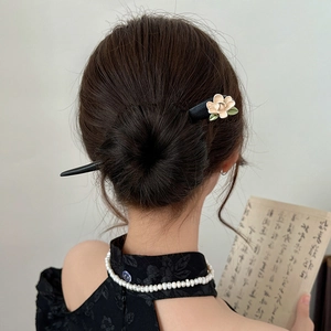 Detailed close-up of a vintage wooden hair stick with cream floral and green leaf accents