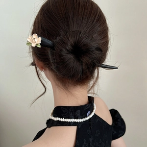 Detail of vintage wooden hair pin with white flower on elegant black dress