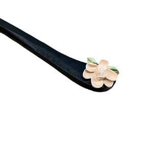 Vintage wooden hair pin with cream flower and green leaf detail on a white background