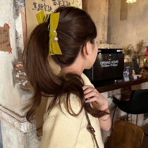Détail d'une pince à cheveux en velours jaune moutarde avec perles sur queue de cheval