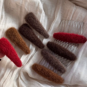 Elegant oval plush hair comb set in warm winter tones on soft white fabric background