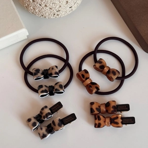 Detailed set of leopard print bow hair ties and France handmade clips on white desk