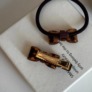 Close-up of leopard pattern bow hair tie and acetate rectangle clip set in white box