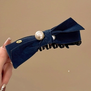 Détail du nœud en velours bleu foncé avec perles blanches et badge doré Love