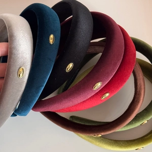Detail of high-top velvet headbands in various colors with elegant golden metal logos