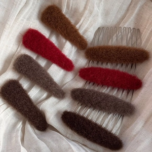 Fuzzy oval plush hair combs and clips set in warm autumn colors on white fabric