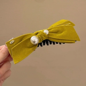 Détail d'une pince à cheveux en velours jaune avec perles et étiquette dorée Love