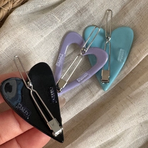 Nahaufnahme von herzförmigen Acetat-Haarspangen in Schwarz, Violett und Blau mit Metallclip