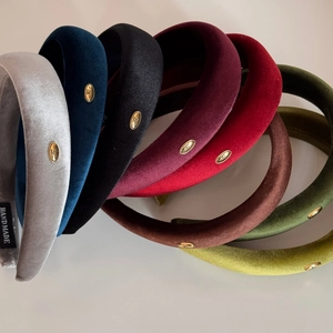 Detail shot of multi-color thick velvet headbands featuring handmade labels and metal accents