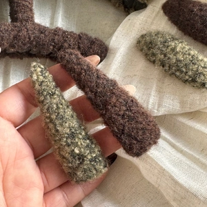 Close-up of wool-felt branch hair clips in brown and moss green with plush texture
