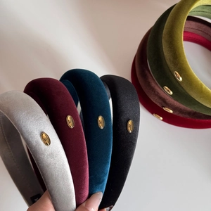 Detail showing various colors of velvet padded headbands with gold handmade metal labels
