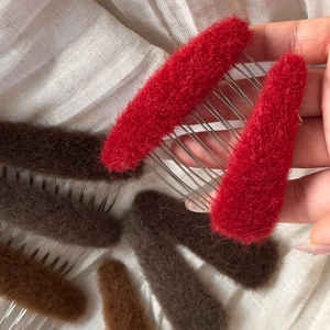 Detailed view of plush oval hair combs in red and brown with metal teeth for women