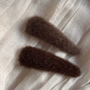 Detailed view of two plush teardrop hair clips in dark brown and coffee faux fur