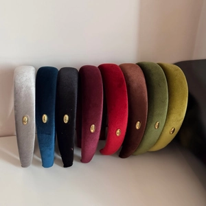 Multiple colors of padded velvet headbands with metallic gold logos in a row