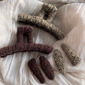 Close-up of plush lamb wool hair claws and water drop clips in brown and beige tones
