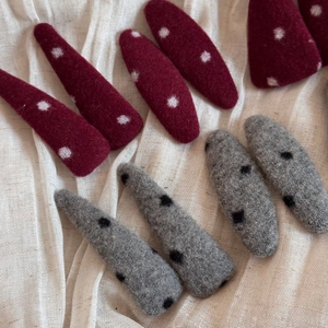 Barrettes à cheveux en feutre rouge et gris à pois sur fond de tissu blanc minimaliste