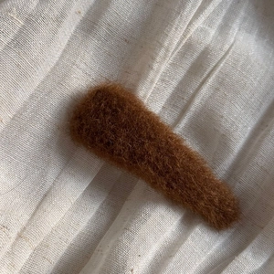 Detail of coffee brown fuzzy oval hair comb clip with soft plush texture on linen background