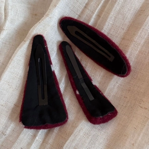 Détail de barrettes bordeaux à pois avec clips métalliques noirs et texture en peluche