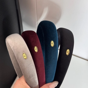 Detail showing four velvet headbands with handmade golden metal tags in multiple colors