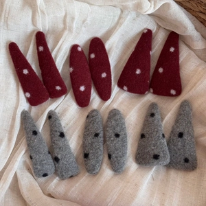 Détail de 12 barrettes en feutre avec pois rouges et gris sur un tissu doux en coton