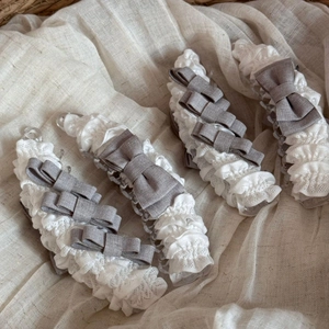 Detailopname van haarklemmen met witte kantruches en een grijze linnen strik