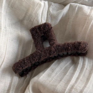 Close-up of a coffee brown plush hair claw clip with a hollow square design on linen fabric