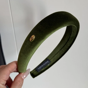 Detailed close-up of olive green velvet headband with handmade metal tag and premium texture
