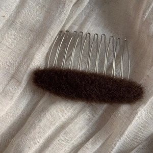Close-up of a brown fluffy hair volume pad with silver 10-tooth metal insertion comb