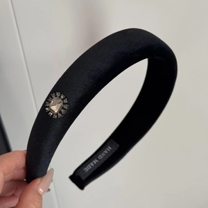 Detailed view of black velvet headband with elegant oversized crystal and handmade label
