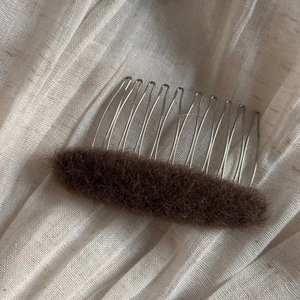 Close-up of 12-tooth metal hair comb with dark brown plush sponge pad for volume