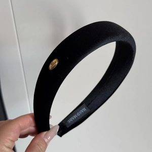 Detail view of the black velvet padded headband featuring a gold Handmade metal tag