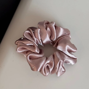 Detail of a dusty rose satin scrunchie with sparkling rhinestones for hair