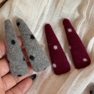 Détail de barrettes en laine feutrée rouge et grise à pois avec texture fibreuse douce