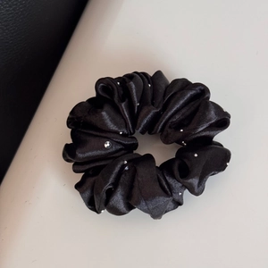 Detail shot of black satin scrunchie with sparkling rhinestones and elegant fabric folds