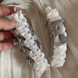 Detailopname van witte kanten bananenklem met een elegante grijze strik van lint