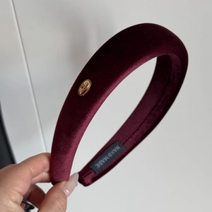 Close-up of burgundy velvet padded headband showing the handmade label and gold logo