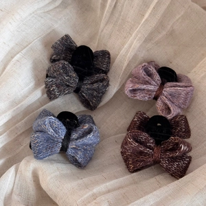 Lot de quatre barrettes à nœuds tricotés en gris, mauve, bleu et marron sur lin