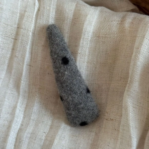 Texture détaillée d'une pince à cheveux en feutre gris à pois noirs sur lin beige