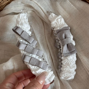 Elegante bananenklemmen met witte ruches kant en grijze strikken voor een kapsel