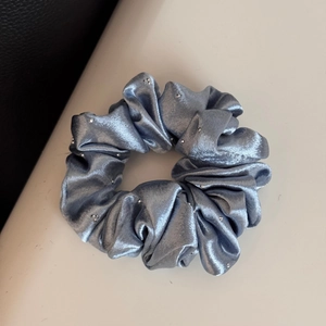 Macro shot of light blue satin scrunchie featuring sparkling rhinestone accents and rich folds