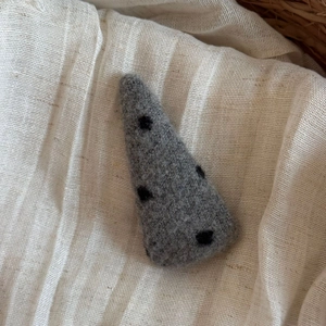 Détail de la pince à cheveux en feutre gris avec pois noirs sur fond en tissu