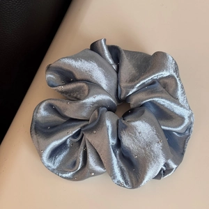 Detailed close-up of blue satin scrunchie with sparkling silver rhinestones and silky texture