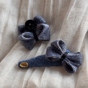 Détail de pinces à cheveux en tricot bleu avec étiquette en métal doré Hand Made