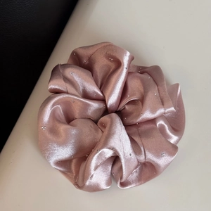 Detailed macro view of pink satin scrunchie with sparkling rhinestones and silk texture