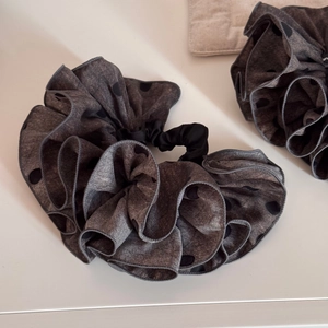 Détail d'un chouchou géant gris à pois avec une texture de tissu plissé élégante