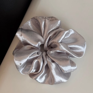 Detail of silver grey satin scrunchie with sparkling rhinestones and silk-like texture
