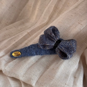 Vue détaillée d'une barrette à cheveux nœud en tricot bleu avec plaque en métal doré