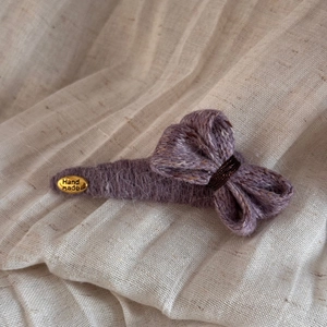 Détail d'une barrette à cheveux en tricot violet fait main avec une plaque dorée